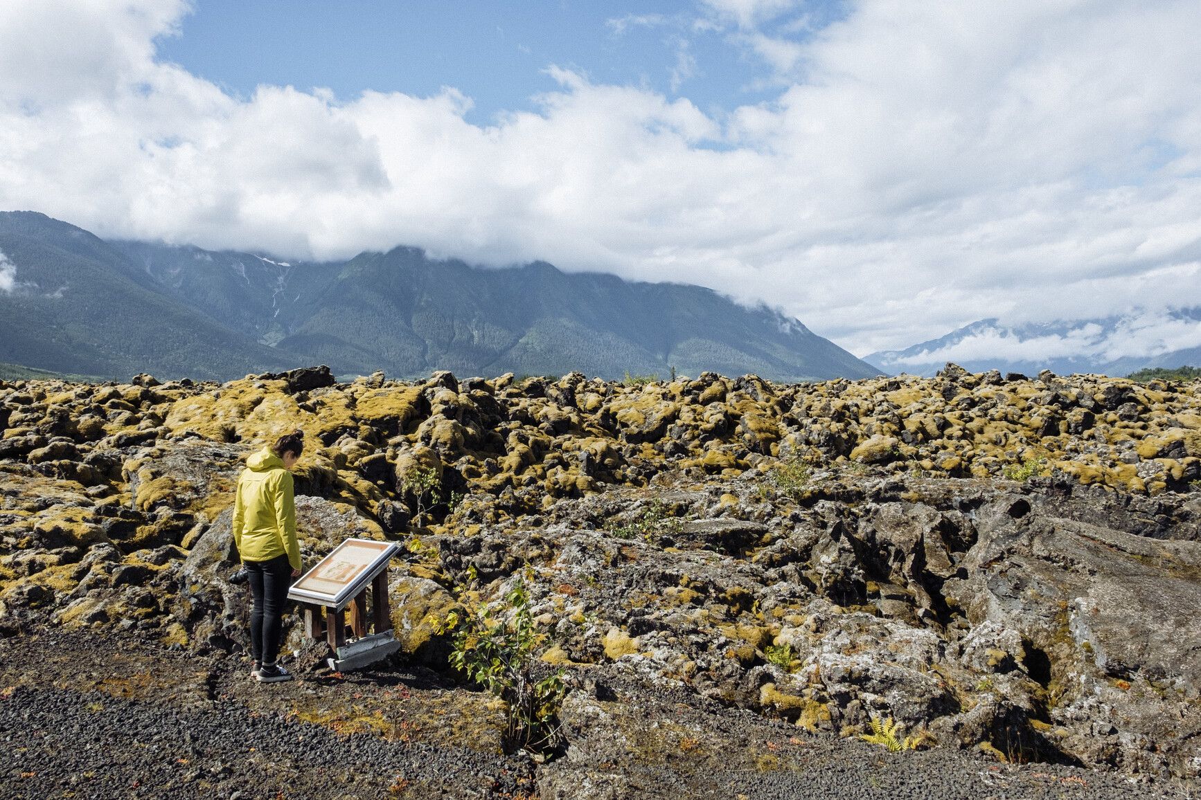 A park visitor reads an information sign beside the vast lava bed in Nisg̱a'a Memorial Lava Bed Park, learning about the powerful volcanic eruption that shaped this culturally and geologically significant terrain. Courtesy of Destination BC