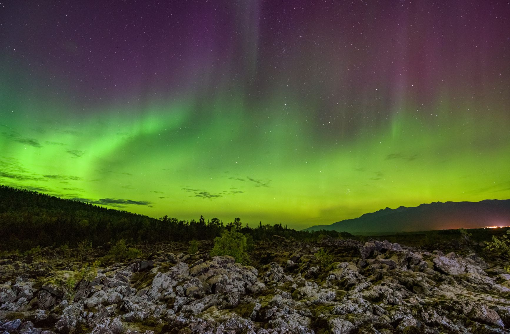 The northern lights dance above ancient lava beds in Anhluut'ukwsim Lax̱mihl Angwinga'asanskwhl Nisg̱a'a Park, casting a surreal glow over this sacred landscape shaped by fire and time. Courtesy of Destination BC