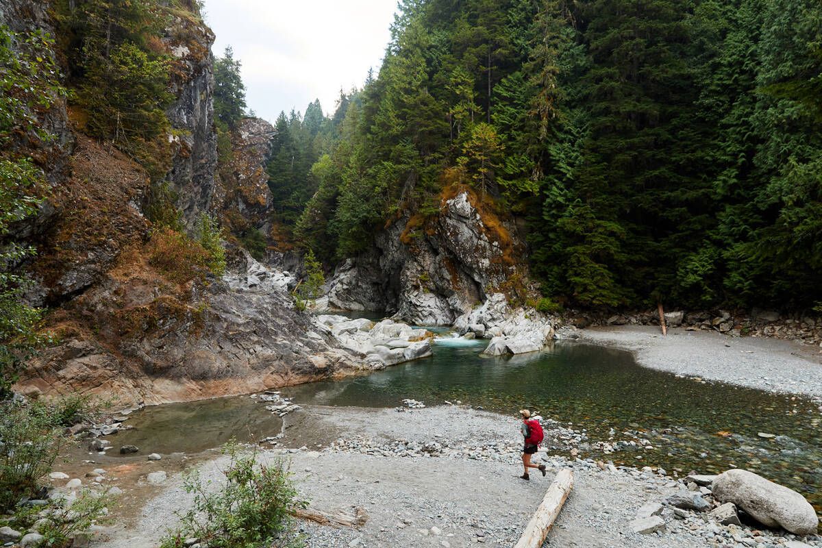 Hiking beside the clear waters of Kleanza Creek, surrounded by forest and cliffs in Kleanza Creek Park. Courtesy of Destination BC