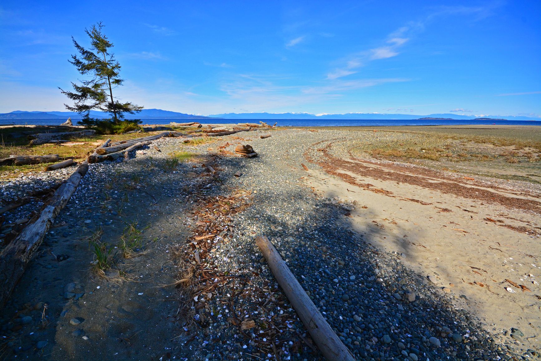 A view of the beach and mountains from the berm. Rathtrevor Beach Park.