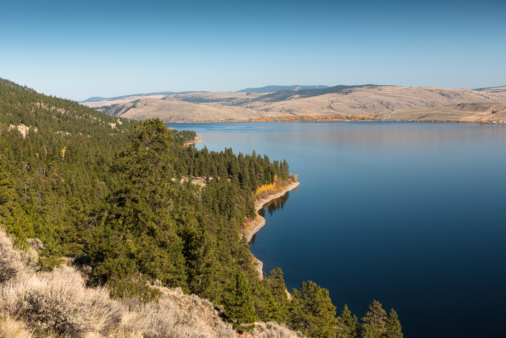 Photo of lake shore with rolling hills in the background.