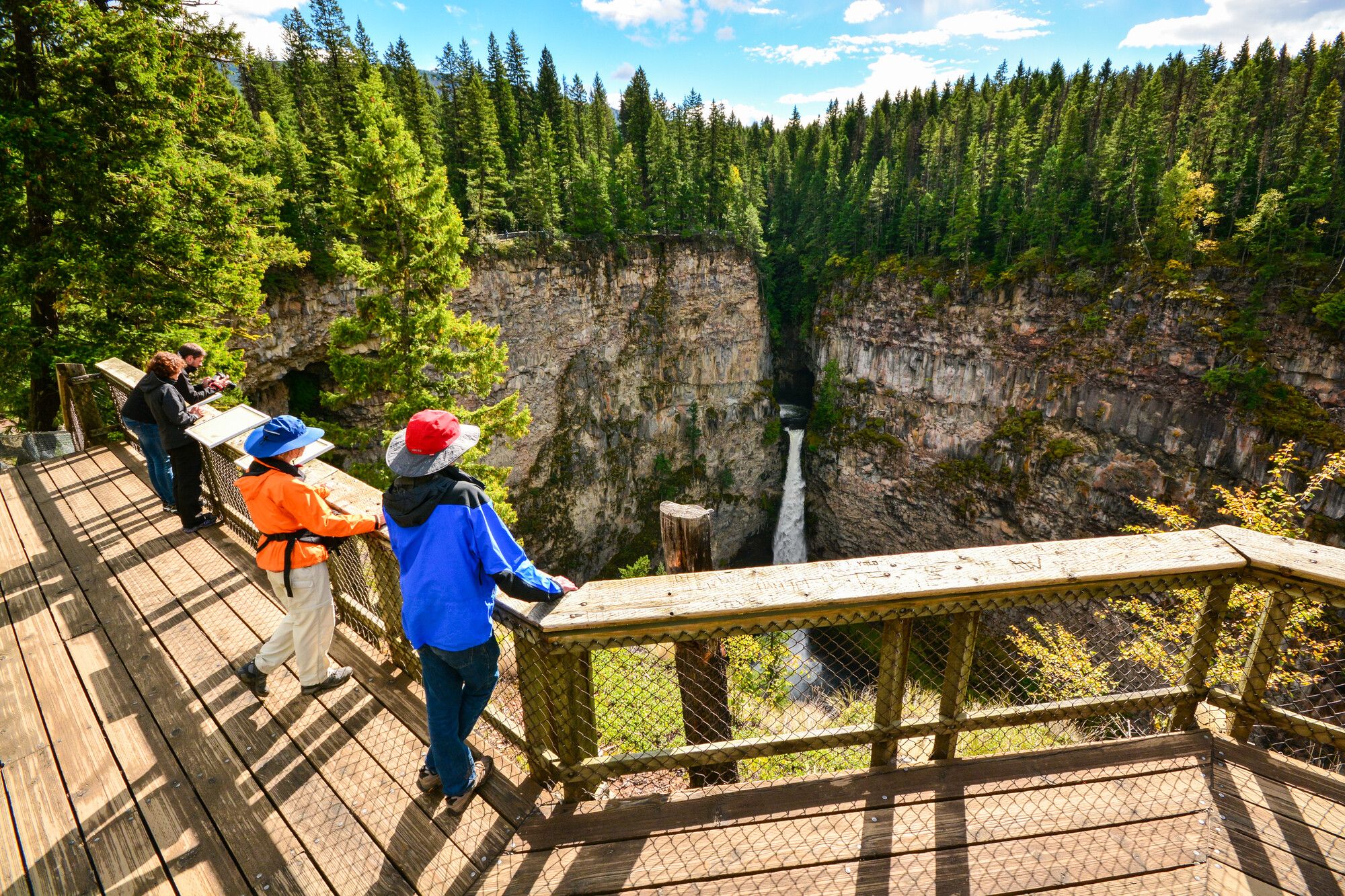 Park visitors marvel at Spahats Falls from the elevated viewing platform on a sunny fall afternoon. Wells Gray Park.