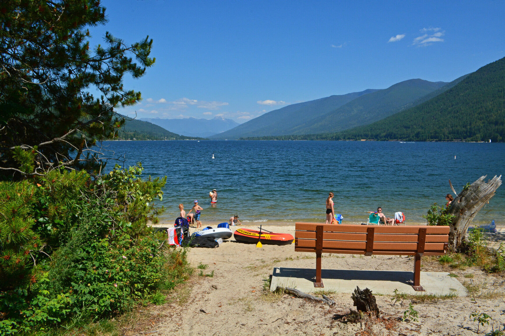 Families at beach with kids. View of lake and mountains.