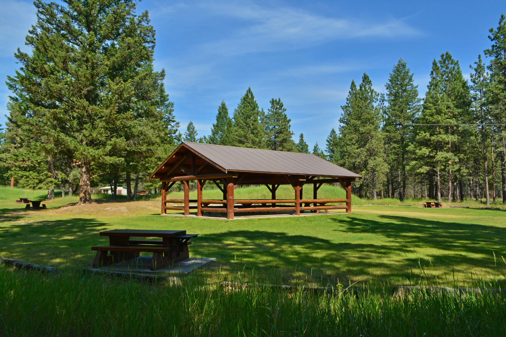 Picnic shelter and picnic tables in grassed area of park.