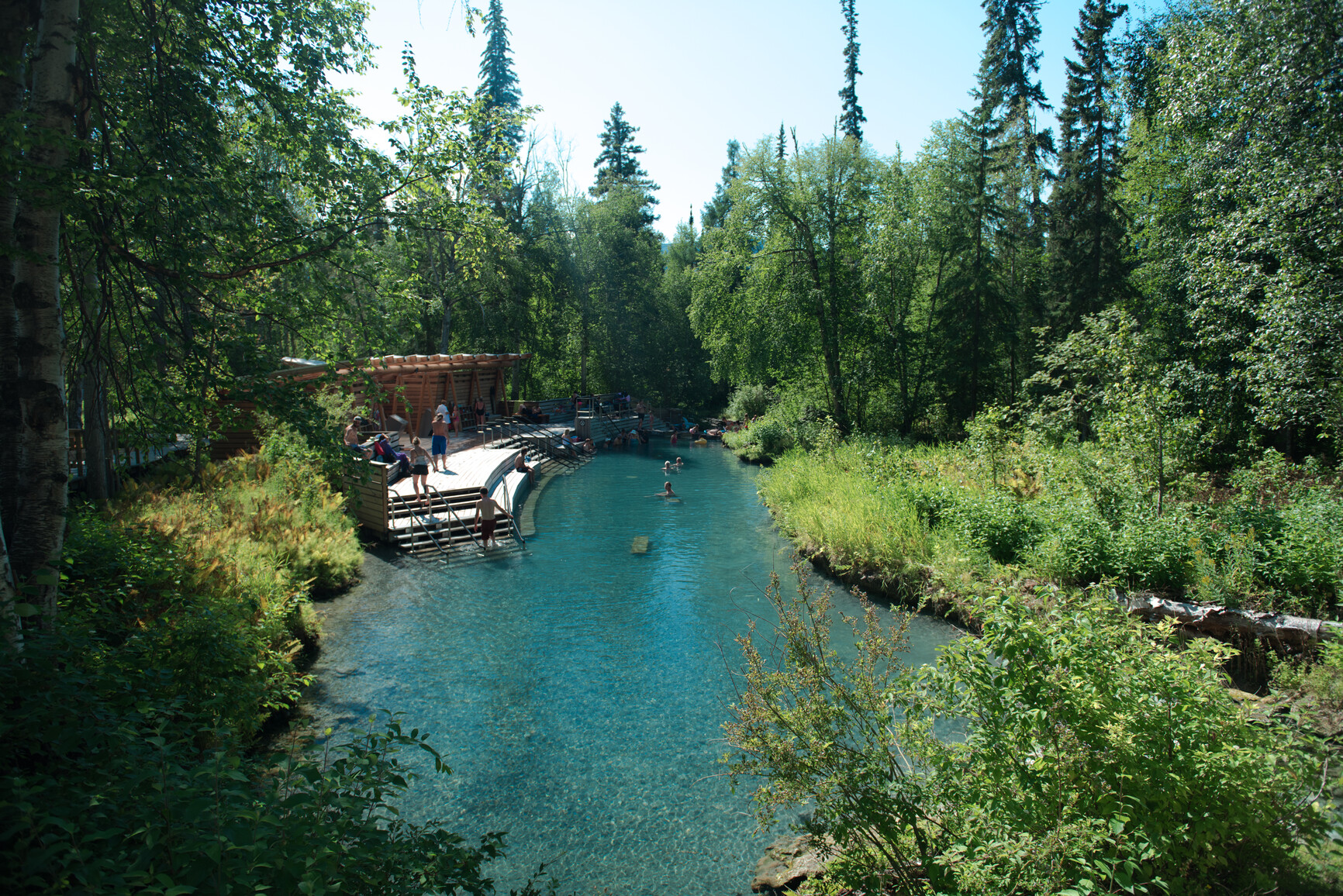 Park visitors enjoying the blue water of Alpha pool. Liard River Hot Springs Park.