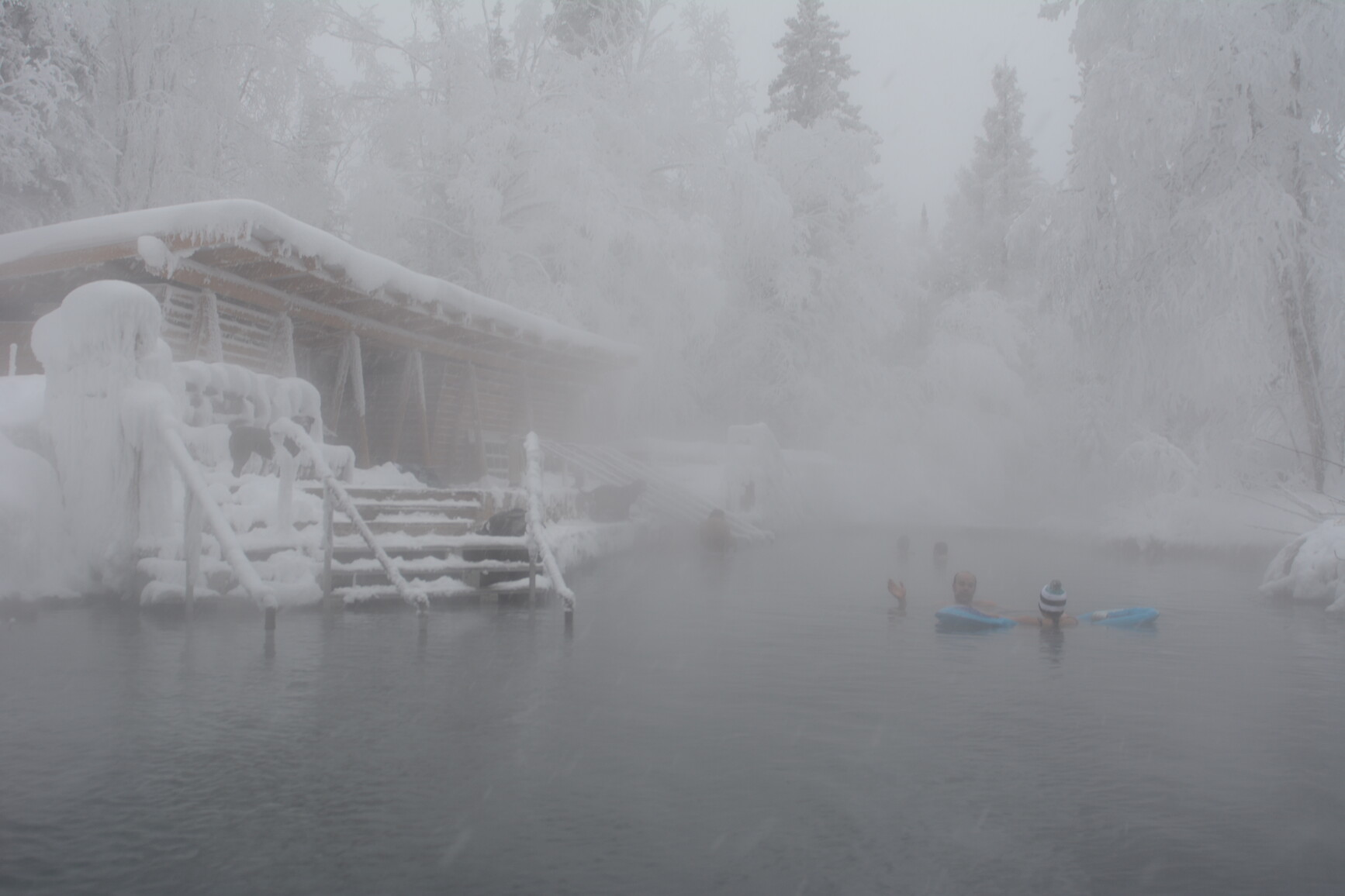 Laird River Hot Springs facility. Though the mist, park visitors are seen enjoying Alpha pool with water temperatures ranging from 42°C to 52°C.