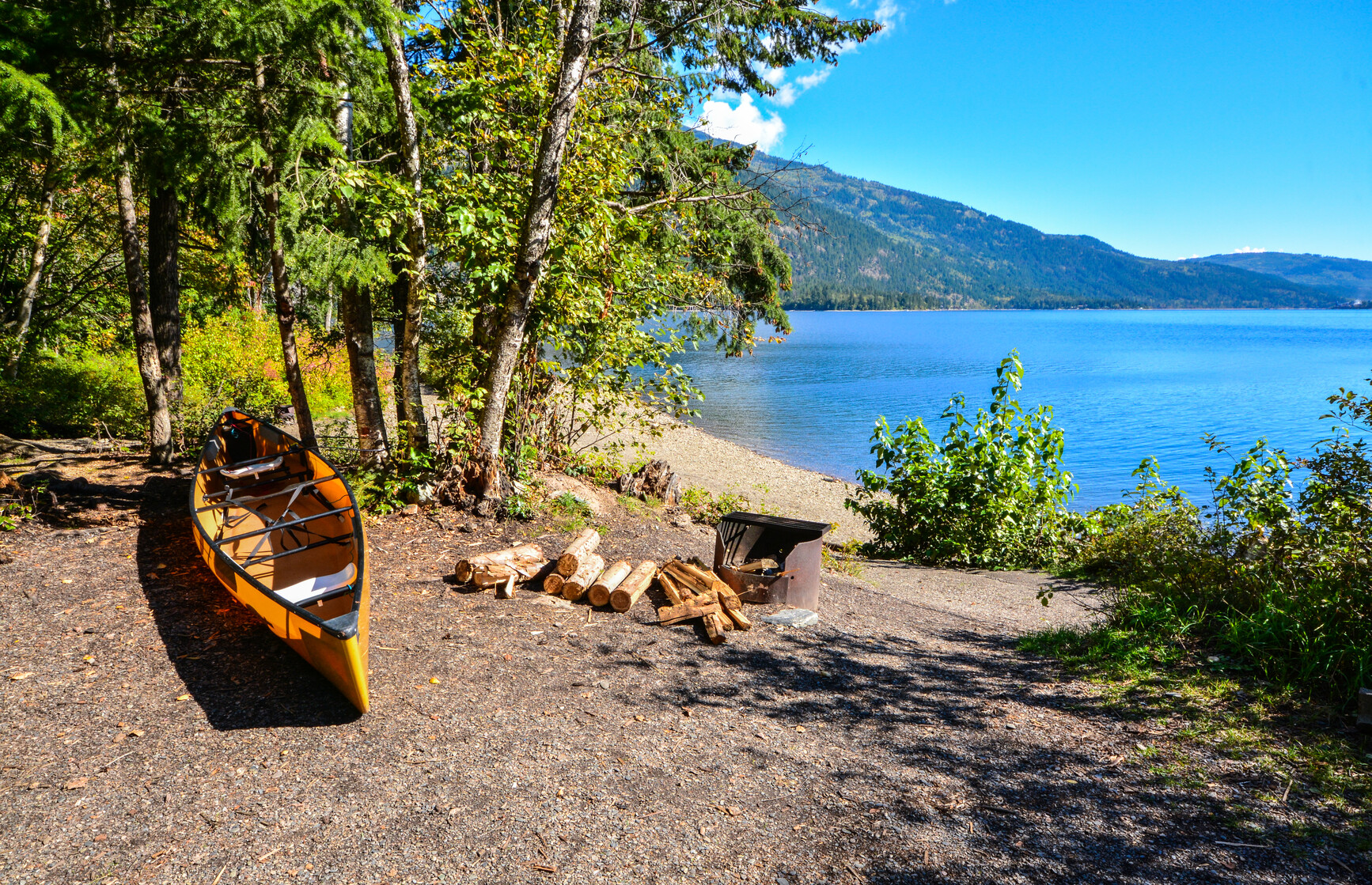 A canoe in a lakeside campsite with a view of Adams Lake.