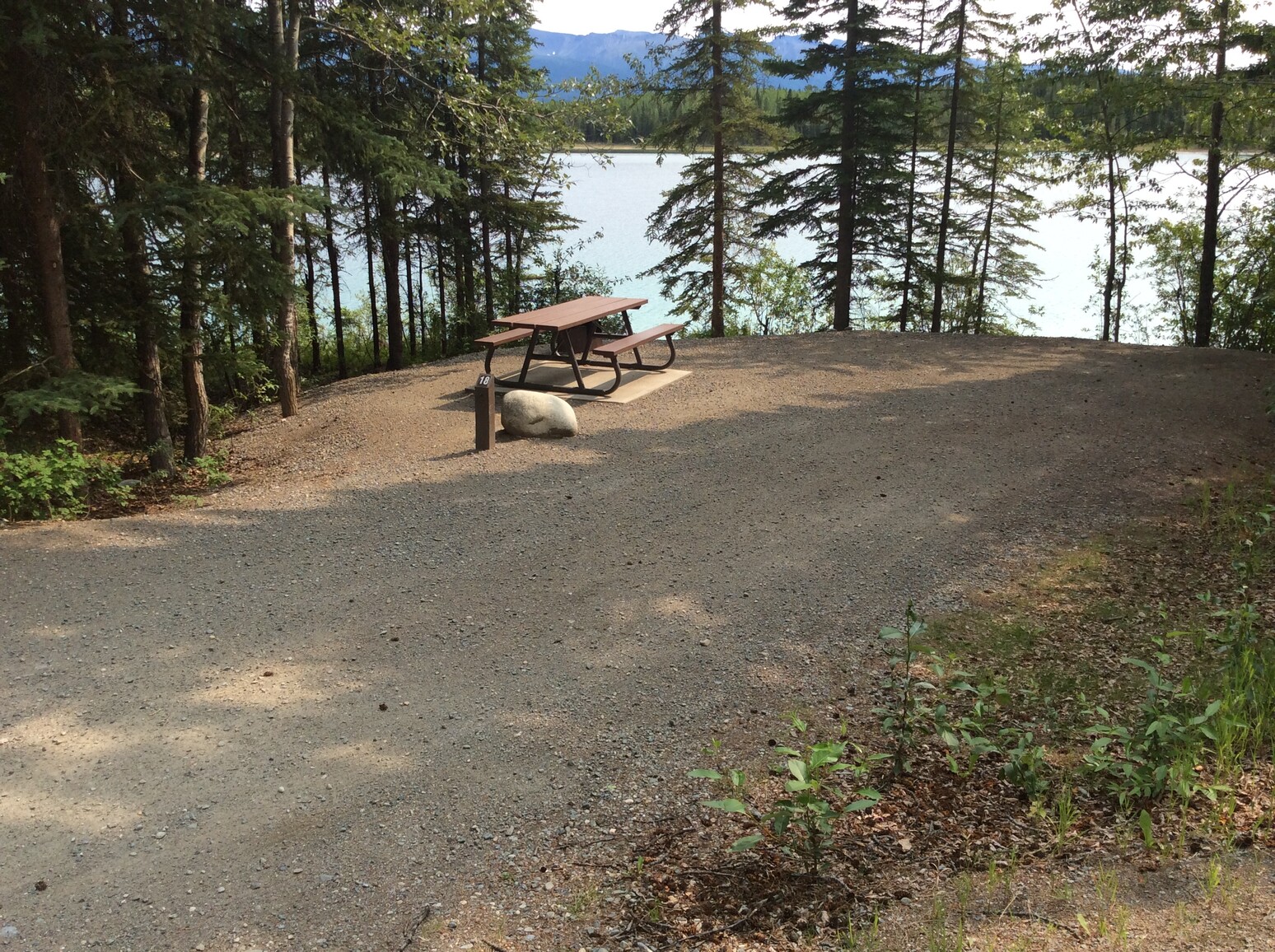 A gravel campsite with a picnic table overlooking the lake.