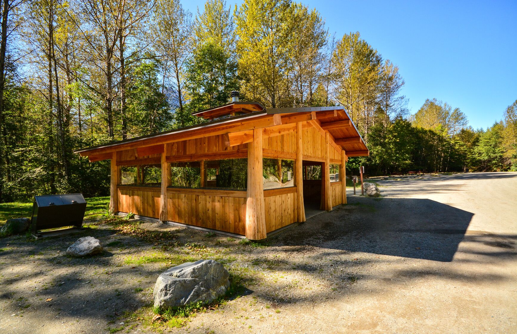 Fisheries Pool Campground shelter in Tweedsmuir Park. Inside the shelter are picnic tables and a fireplace.