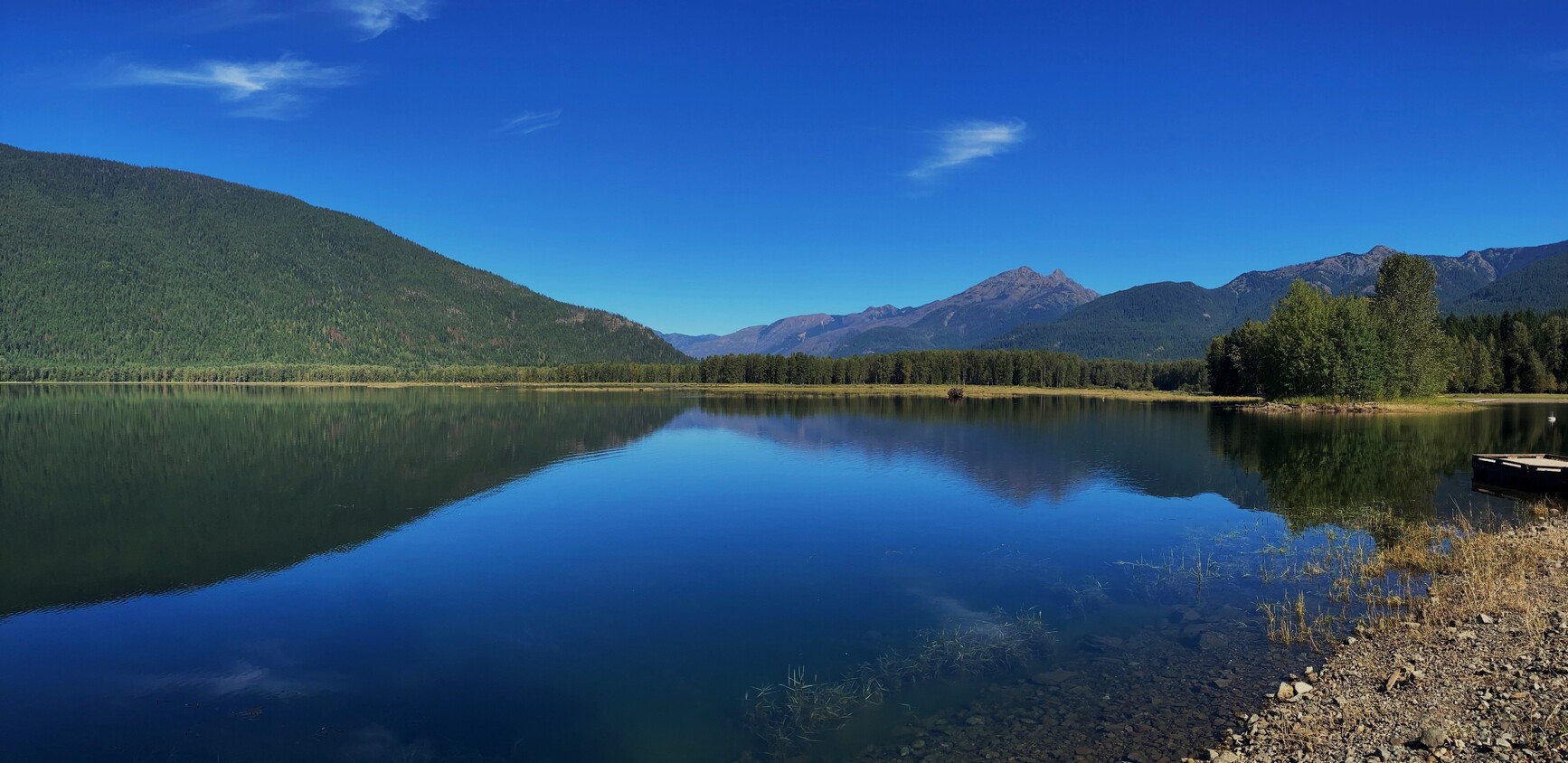 Mountains and blue skies reflect on Ross Lake in Skagit Valley Park. 