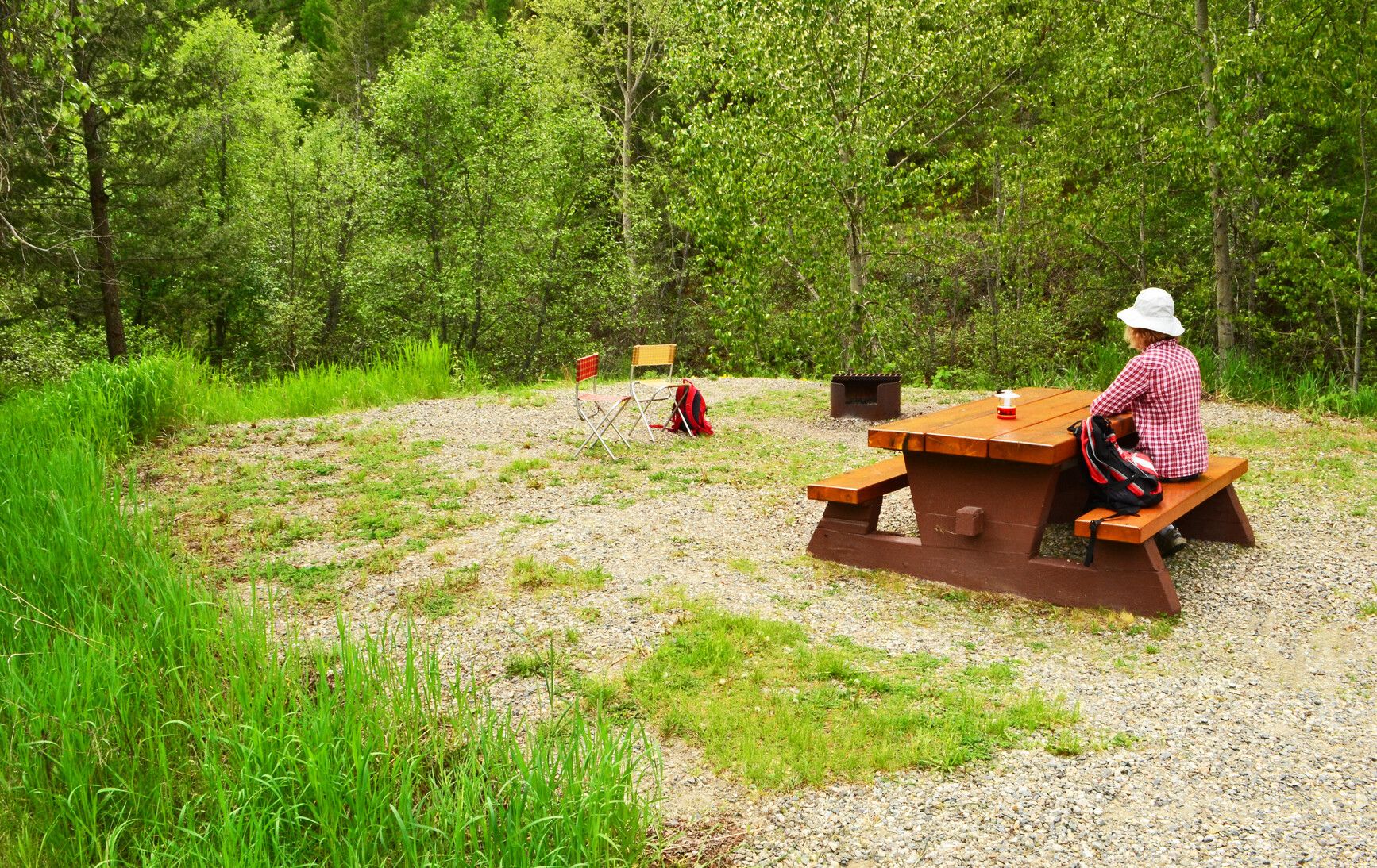 A park visitor sitting at a picnic table in a campsite in Boundary Creek Park.