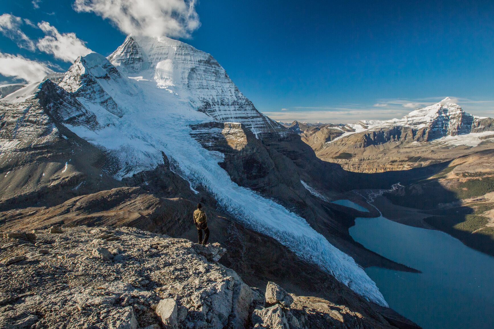 A park ranger stands on the summit of Rearguard Mountain in Mount Robson Park. View of Mount Robson, Berg Glacier and Berg Lake.