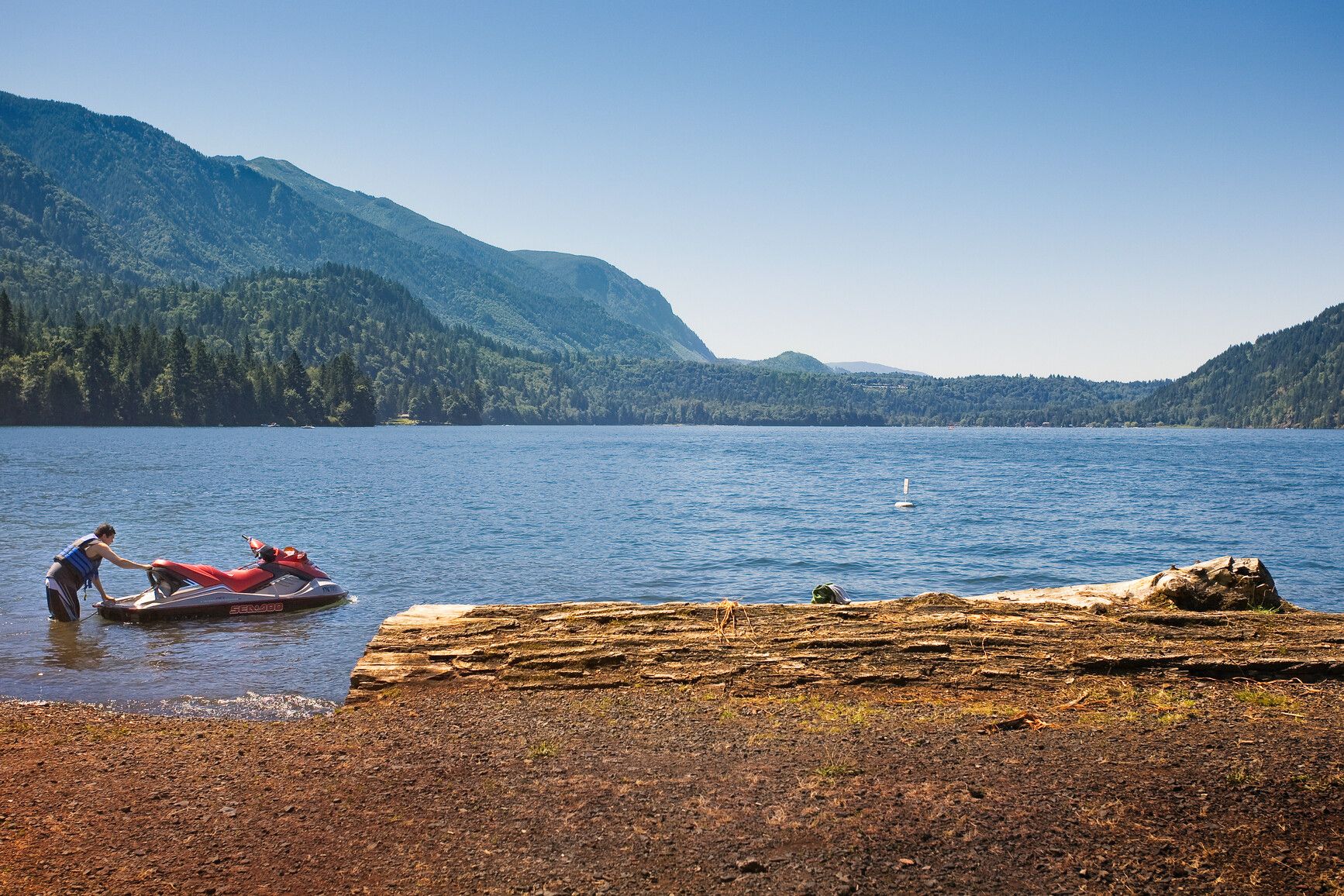 A beautiful, clear day on the lake, invites a park visitor for a ride on their personal water craft. Cultus Lake Park.