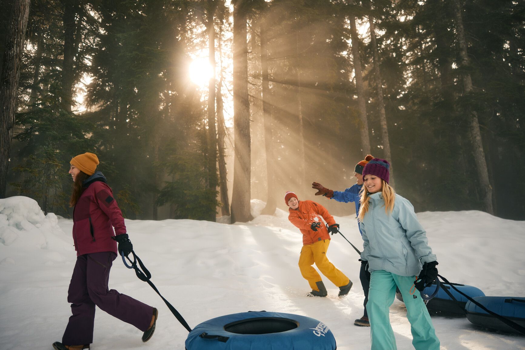 A family pulling tubes over the snow on their way to go tubing down the mountain in Cypress Park. Credit: &nbsp;Destination Vancouver/Kindred and Scout