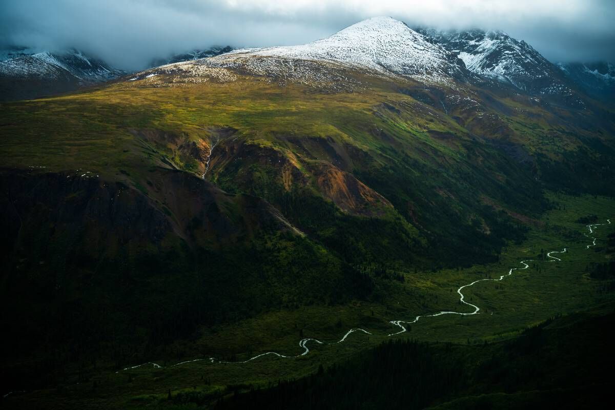 Spatsizi Plateau Wilderness Park unfolds in layers of alpine beauty, where a river meanders like silver ribbon through lush valleys beneath snow-draped peaks and a sky brushed with northern light. Courtesy of Destination BC