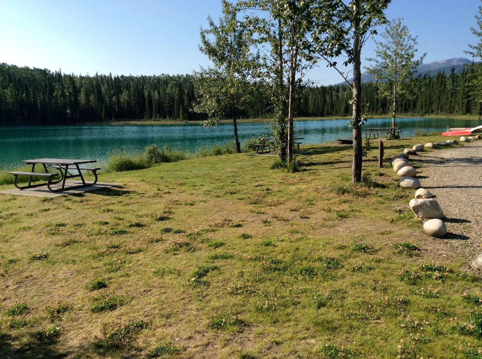 Along the shoreline of the clear blue waters of Boya Lake lies the grassy picnic area in Tā Ch'ilā Park, a peaceful place to relax and enjoy nature.