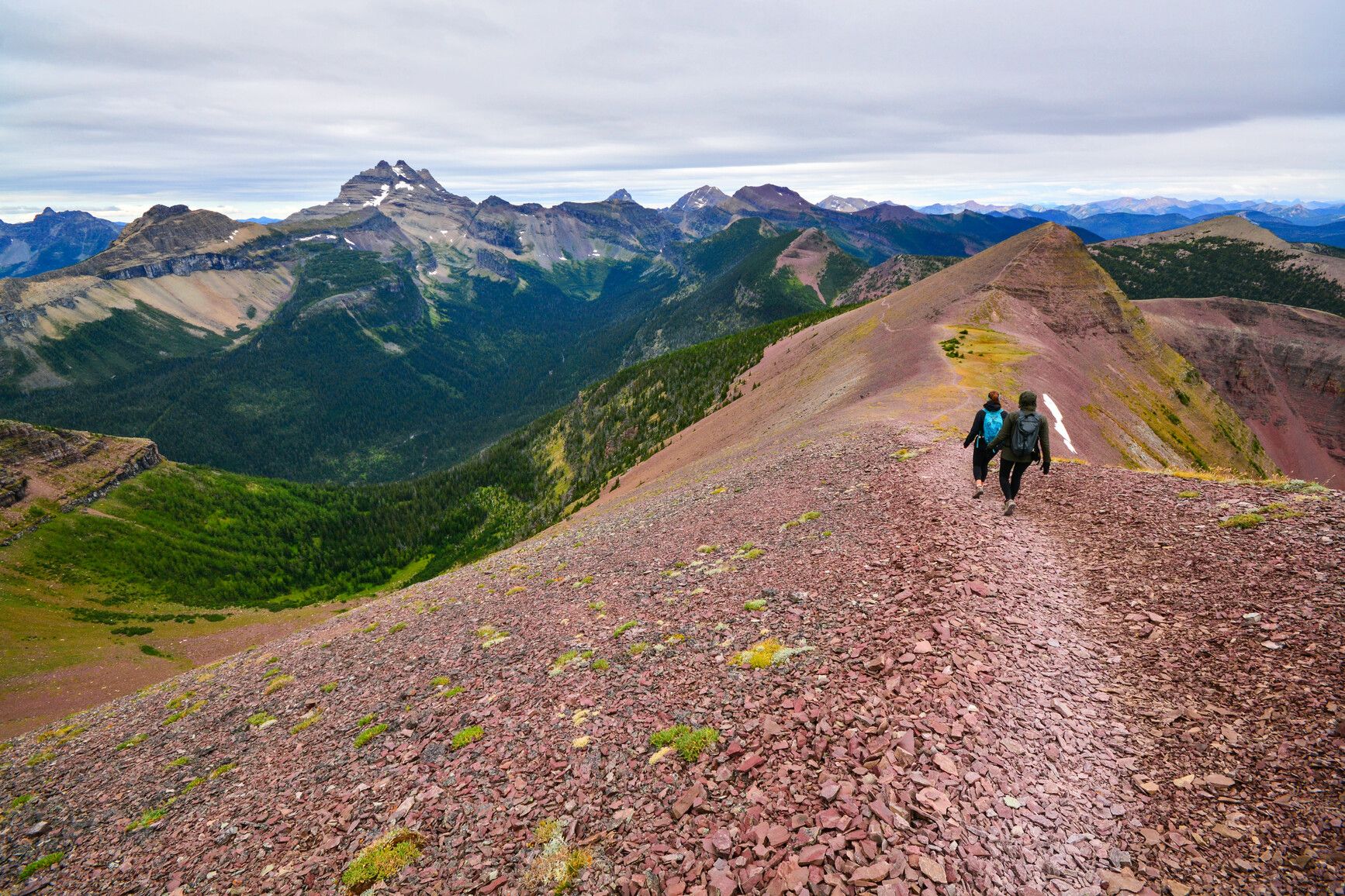 Hikers walk along Akamina Ridge in Akamina-Kishinena Park. The ridge reaches an elevation of 2,575 meters. The U-shaped valley on the left has been carved by a glacier​.