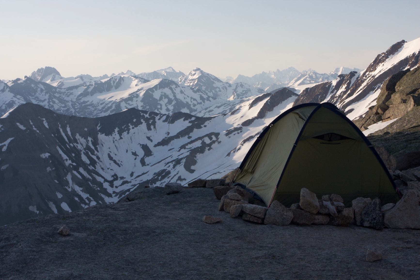 A tent on the cliffside facing the snowcapped mountains in the distance. Photo credit: Destination BC