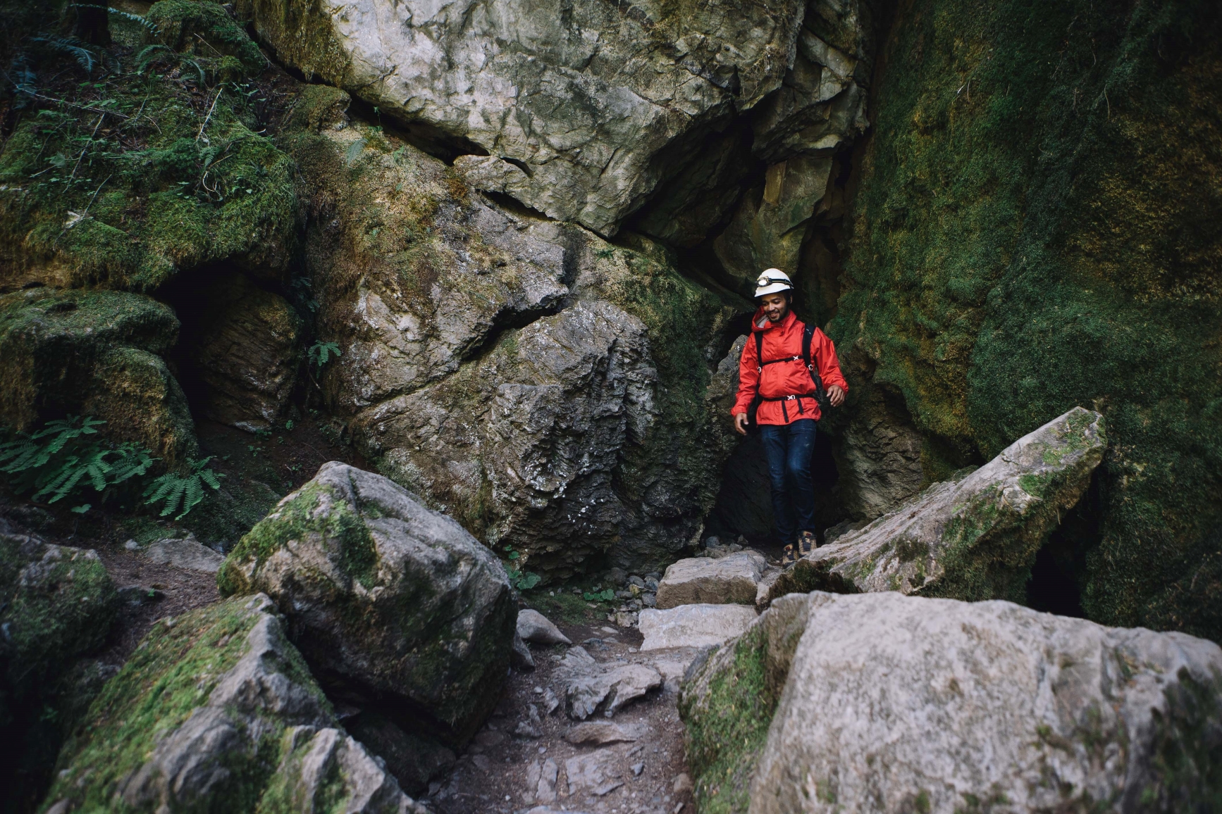 A park visitor with climbing gear and a helmet navigating through the rocky cave terrain.