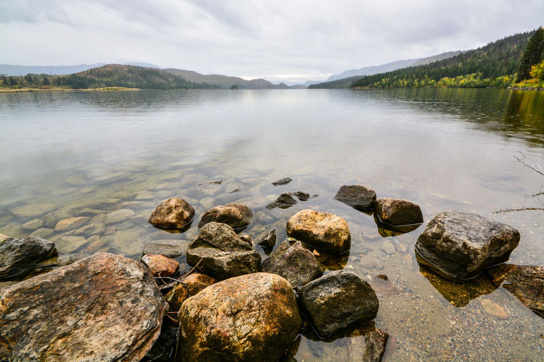 Experience the serene beauty of Niskonlith Lake as rain gently ripples its calm surface.