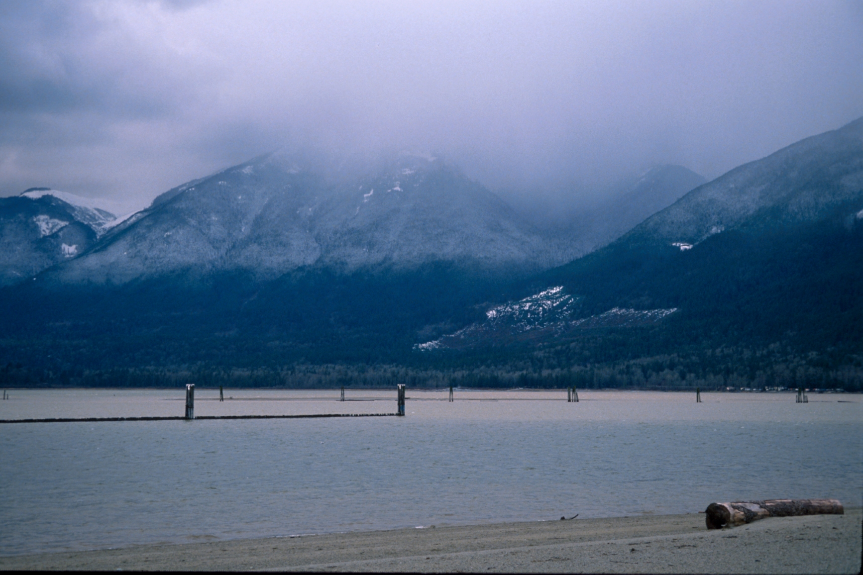 View from the shoreline of the lake and snowcapped mountains in the distance.