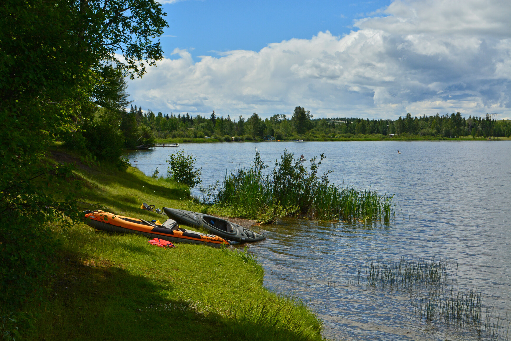 Kayaks on the shore of Ten Mile Lake. In the background is the dock and a boat.