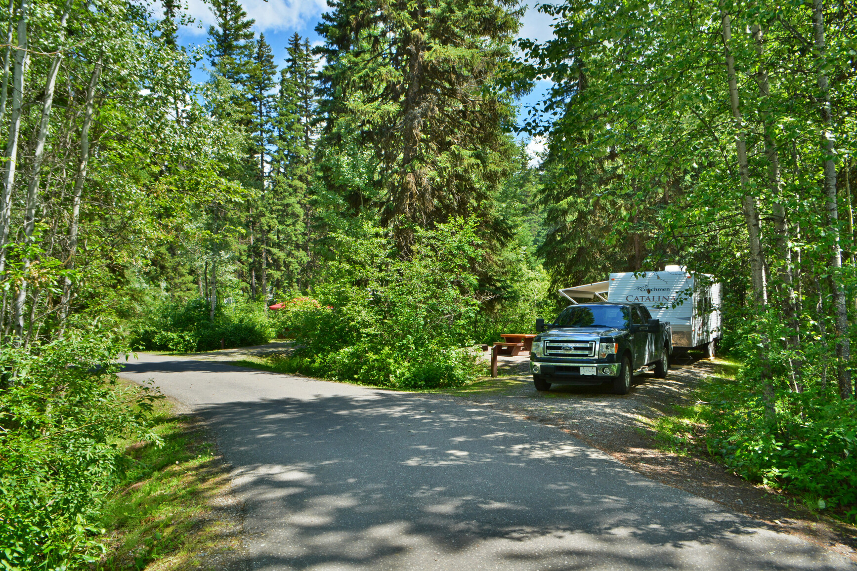 The campground at Ten Mile Lake. A truck and trailer are in on site. The campground location is in the forest.
